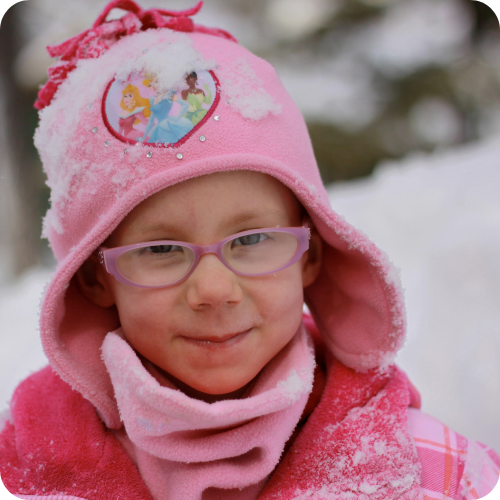 ashlynne in winter hat and coat surrounded by snow