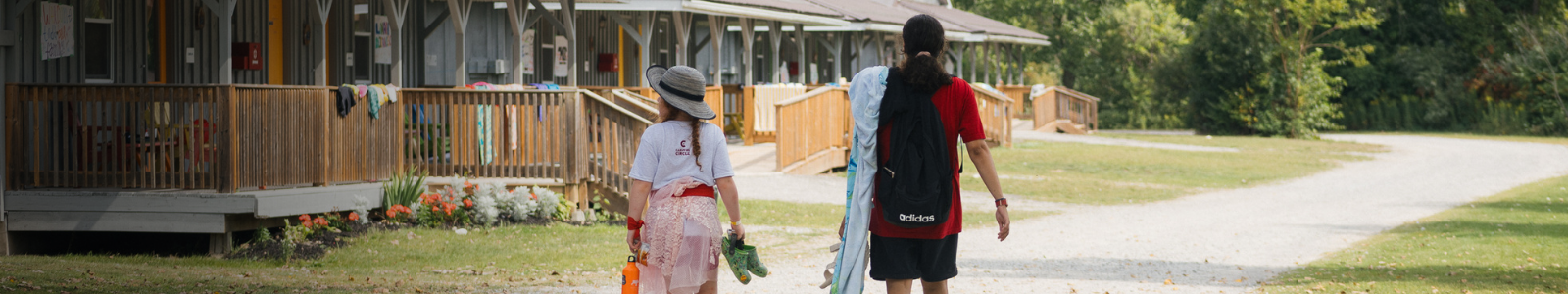 camper and parent walking on camp grounds on a sunny day in swim gear