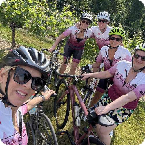 group of tour riders outside in the sunshine surrounded by vineyard and trees